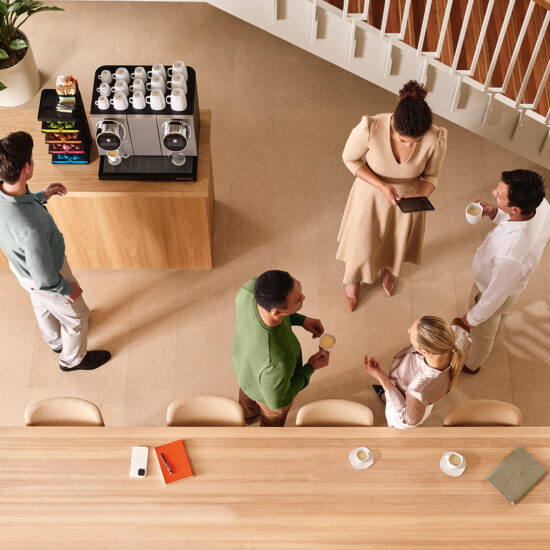 Exploring the link between coffee and productivity in the workplace A group of colleagues socialising at work and using a Nespresso coffee machine.
